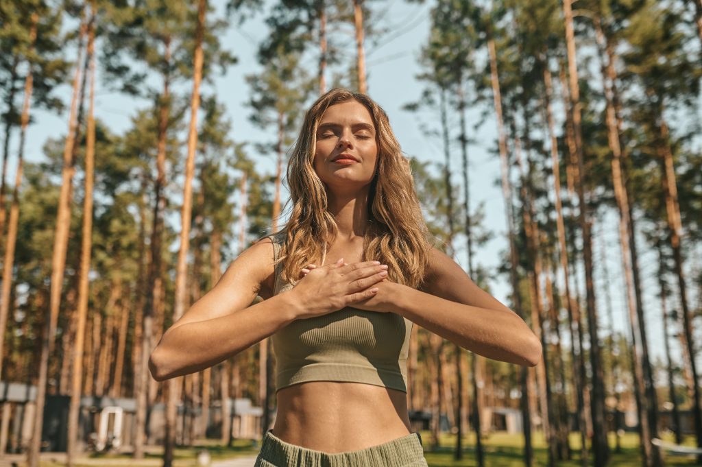 Relaxation. Cute blonde woman practising yoga outside and looking relaxed